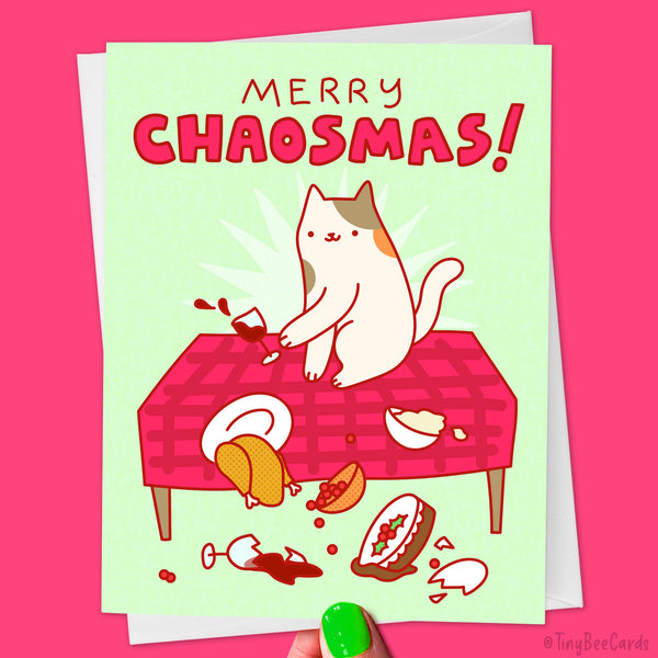 Hand drawn greeting card with an illustration of a cat knocking all of the Christmas dinner onto the floor and text saying 'Merry Chaosmas!'