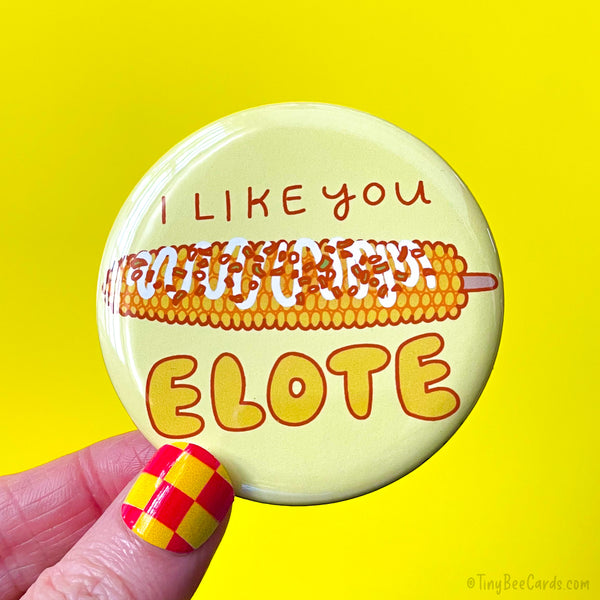 Button badge with a hand drawn elote street corn illustration and 'I like you elote' text on a yellow background