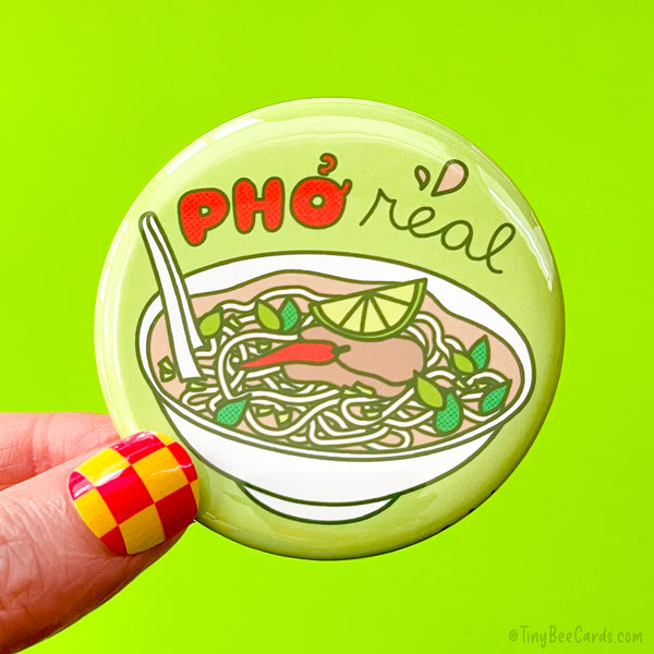 Button badge with a hand drawn design of pho soup and 'pho real' text on a green background.